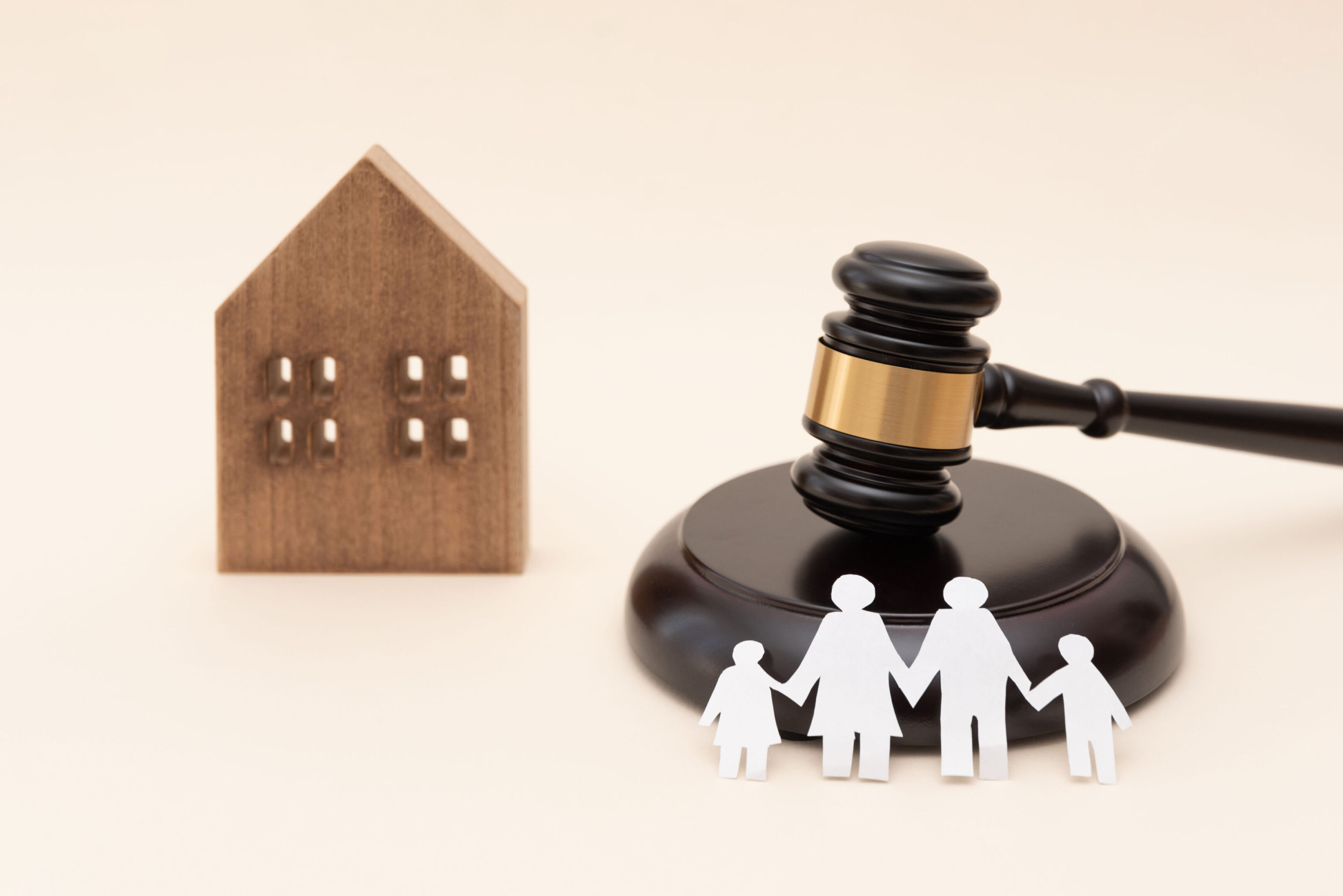 Family law and justice concept with gavel, wooden house model and paper family on neutral background